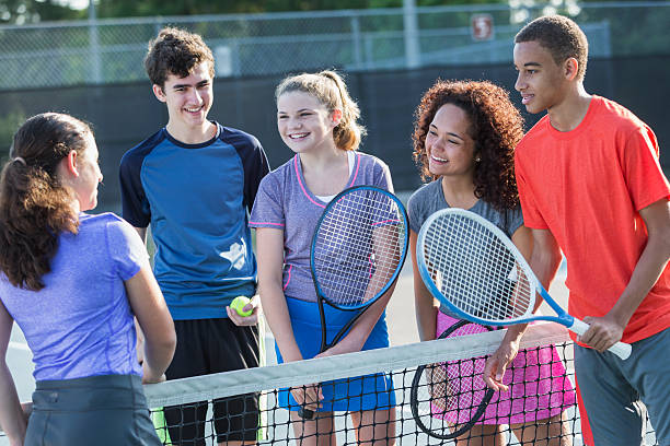 Multi-ethnic teenagers playing tennis.  14 to 17 years.